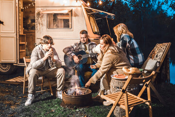 Family trailer travel. Children,brother sister,mom dad fry sausages on fire, eat hot dogs. Evening picnic in nature.Holiday barbecue BBQ food.Vacation weekend dinner.Road lunch.Camper,house on wheels