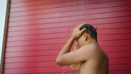Sport man take a rain shower for cleaning at the swimming pool in hotel.