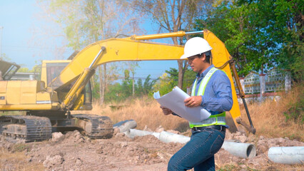 Construction worker controls digging of trench with excavator on site.