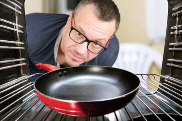 Concept of cooking by men, looking at oven for preparing food. Men cooking at home. View from inside