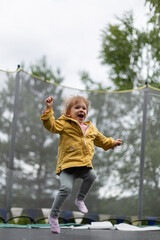 Naklejka premium Little girl jumping on trampoline outdoors
