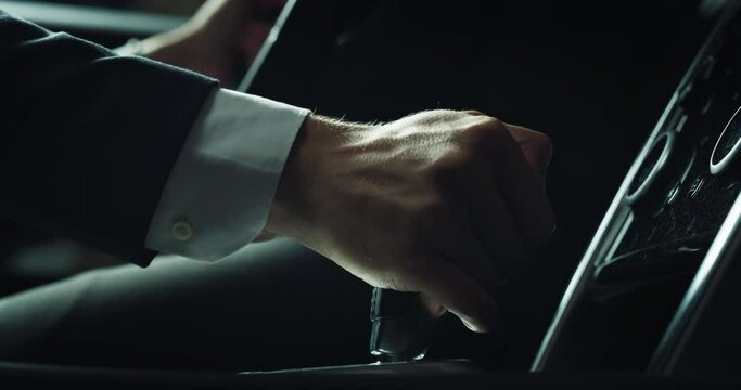 Close Up on the Hands of a Man Adjusting his Gear While Driving in a Fancy Luxurious Car. A Businessman in Trying Out a Car Before Buying it in a Dealership. Concept of Car Advertisement