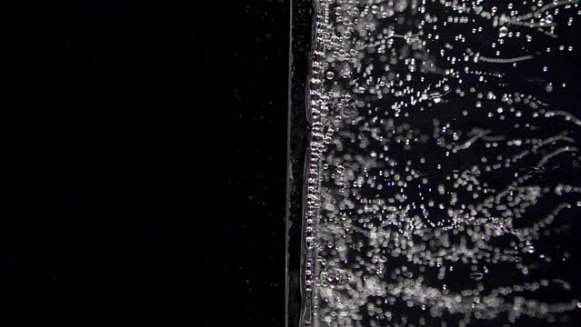 Super slow motion of clean glass with soda mineral water bubbles texture filled with lemon water. Filmed on high speed cinema camera, 4k 1000 fps