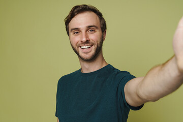 Excited smiling man taking selfie isolated over green wall
