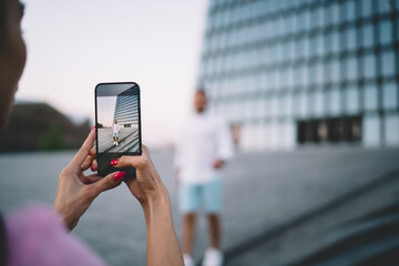 Anonymous woman taking photo of man on smartphone