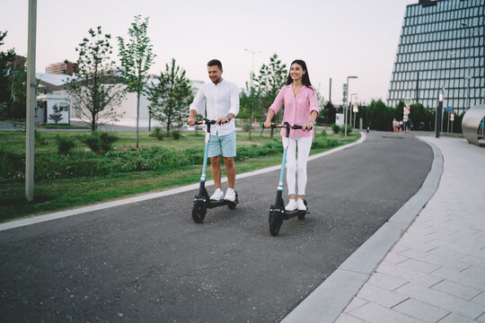 Happy couple riding kick scooters in city - Powered by Adobe