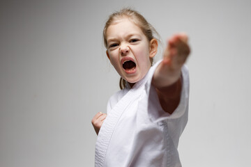 A little girl strikes with her hand in karate, a lesson for children.