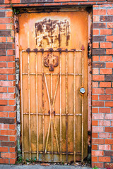 Old Rusted Metal Door and Security Gate Attached to a Brick Wall