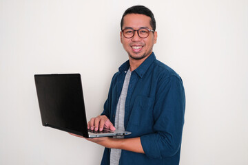 Fototapeta na wymiar Adult Asian man smiling confident while working using his laptop