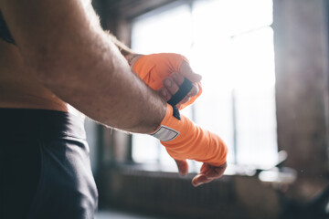 Fototapeta premium Sporty man putting gloves on in gym