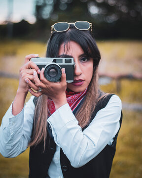 woman with sunglasses taking pictures with analog camera