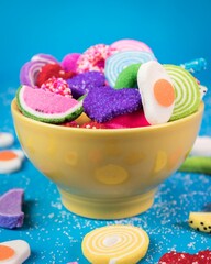 yellow bowl with chopsticks of candies of different shapes and colors