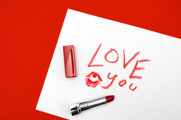 Love text with red lipstick kiss on white background with kiss. The inscription LOVE written in lipstick on a white background, top view. The concept of Valentine's Day February 14