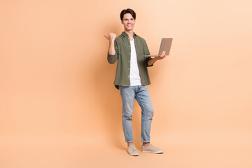 Full length size photo of young cheerful programmer guy wear stylish khaki shirt hold computer...