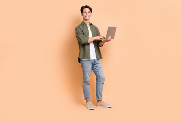 Full body photo of young student guy wearing stylish clothes hold laptop user for distance university education isolated on beige color background