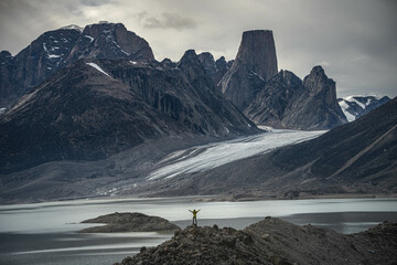 A man standing on a stone cliff in Akshayuk Pass, Nunnavut, Canada. Foggy mountains, cloudy morning...