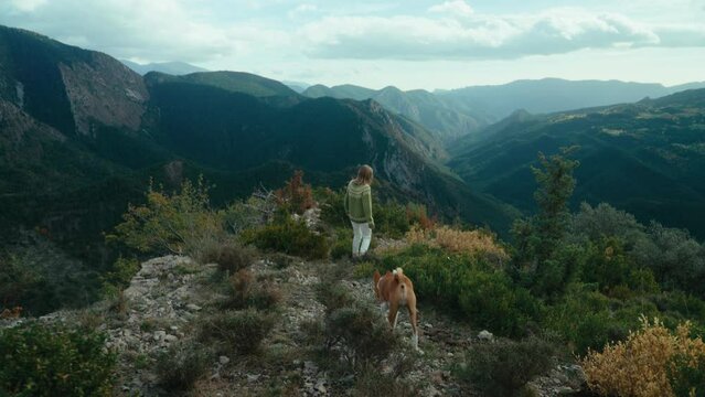 Woman and dog walk in autumn mountains scenery. Outdoor lifestyle, hike with dog, enjoy wild nature. Travel blogger concept 