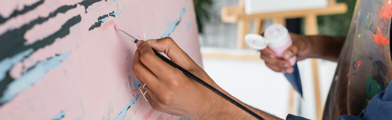 Cropped view of african american artist painting on canvas in workshop, banner.