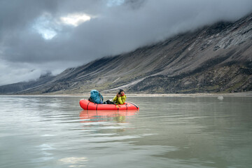 A man rowing packraft on Summit Lake, Akshayuk Pass, Baffin Island, Canada