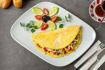 Omelet with cheese, mushrooms and vegetables on a white porcelain plate