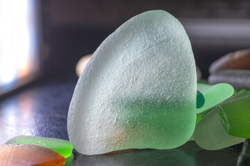 Macro image of colourful backlit pieces of sea glass, white, green and amber pieces