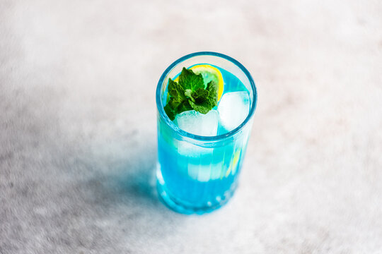 Close-Up of a  blue cocktail with fresh mint and lemon on a table