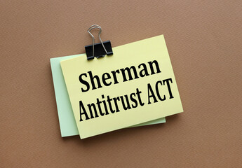 Sherman Antitrust Act text on yellow sticker with clip. on a dark background. brown