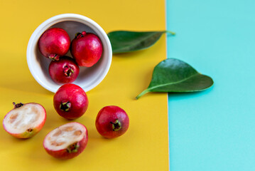 Red cherry guava fruit on green and yellow background (Psidium cattleyanum)