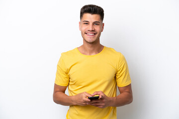 Young caucasian man isolated on white background sending a message with the mobile