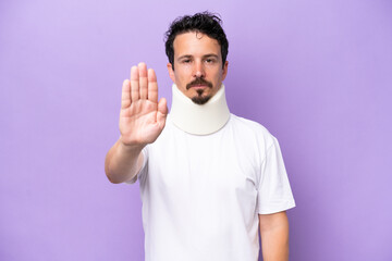 Fototapeta premium Young caucasian man wearing neck brace isolated on purple background making stop gesture