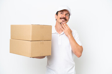 Delivery caucasian man isolated on white background looking up while smiling