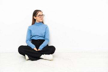 Young Caucasian woman sitting on the floor looking side