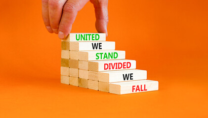 United or divided symbol. Concept words United we stand divided we fall on wooden blocks. Beautiful orange table orange background. Businessman hand. Business united or divided concept. Copy space.