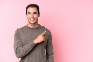 Young caucasian man isolated on pink background pointing to the side to present a product