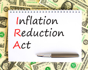 IRA inflation reduction act symbol. Concept words IRA inflation reduction act on white note on a beautiful background from dollar bills. Business IRA inflation reduction act concept. Copy space.