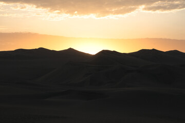 Fototapeta na wymiar Sunset at Huacachina desert in Peru. Desert sunset landscape background silhouette photography. Golden hours at sandy mountains.