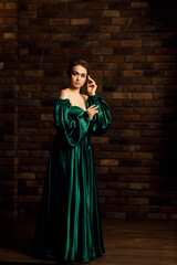 Full-length portraits of a girl in a green dress against a brown brick wall