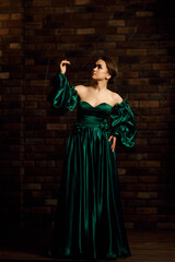 Full-length portraits of a girl in a green dress against a brown brick wall