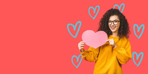 Photo of amazing young woman holding big pink paper heart thinking over right answer on date invitation wears casual isolated over pink background.