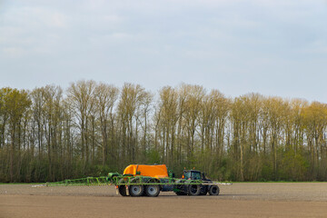 Tractor with a sprayer during spring work in the field