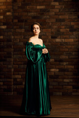 Full-length portraits of a girl in a green dress against a brown brick wall