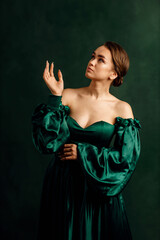 waist portrait of a girl in a green dress standing against a green wall