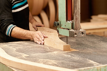 A male carpenter cuts a wooden board