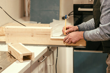 The carpenter marks the dimensions on the board for further cutting, close-up of the carpenter's hands