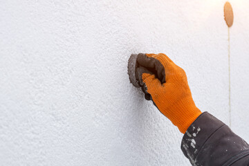 A worker insulates a house with polystyrene, sealing a crack in the house