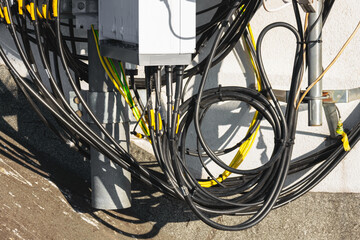 Close-up of a cellular antenna with many power cables, coaxial cables, optical fiber.