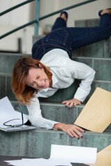 mature businesswoman falling on stairs inside office building