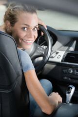 happy woman getting car key in auto show or salon