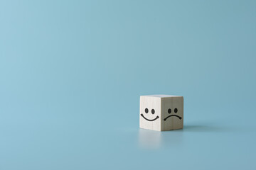 Concept of customer satisfaction review. Wooden blocks with facial expression with Happy and sad mood. To evaluate business performance you need a survey from customer experience.