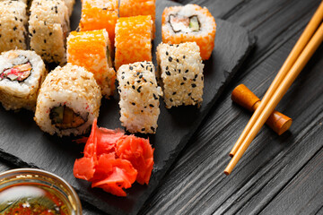 close up of sushi rolls on black tray